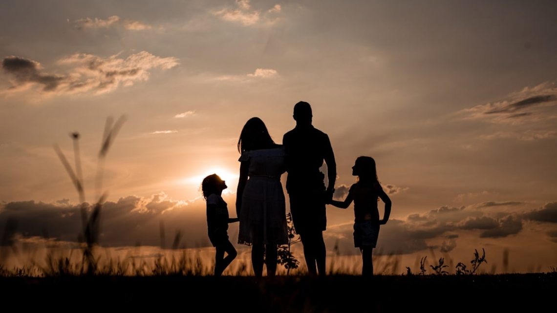 a family standing in a field at sunset