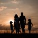 a family standing in a field at sunset